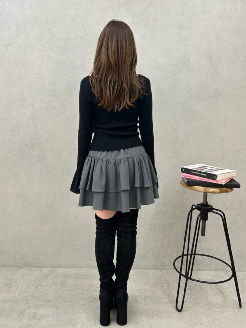 ブラック系のニット/セーター、グレー系のスカート、ブラック系のブーツを着用したレディースの秋コーディネートの3枚目の写真