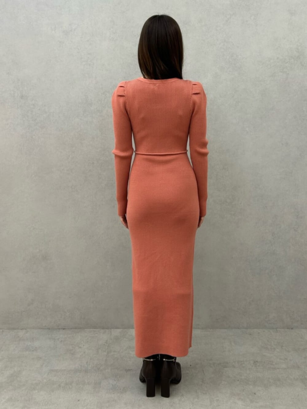 オレンジ系のワンピース、ブラック系のブーツを着用したレディースの冬コーディネートの3枚目の写真