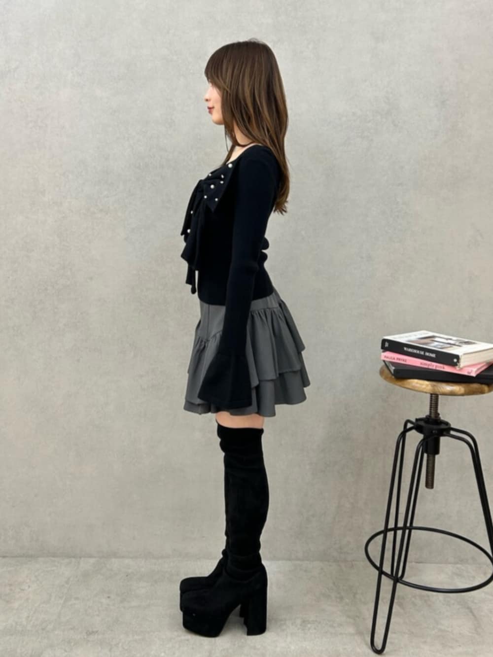ブラック系のニット/セーター、グレー系のスカート、ブラック系のブーツを着用したレディースの秋コーディネートの2枚目の写真