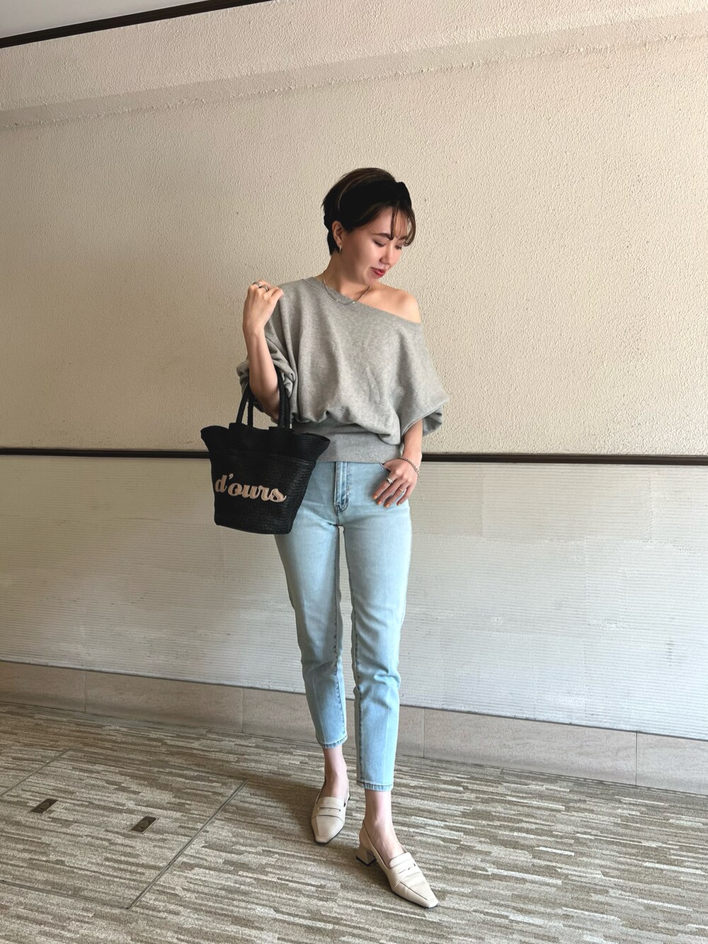 グレー系のスウェット、ブルー系のデニムパンツ、ブラック系のかごバッグを着用したレディースの春コーディネートの2枚目の写真