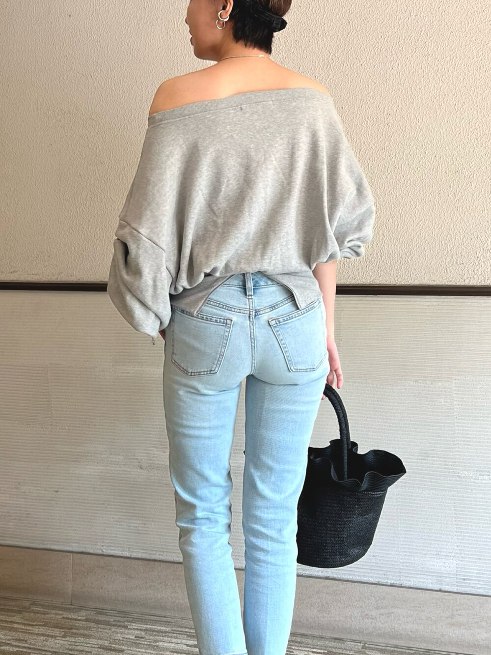 グレー系のスウェット、ブルー系のデニムパンツ、ブラック系のかごバッグを着用したレディースの春コーディネートの4枚目の写真