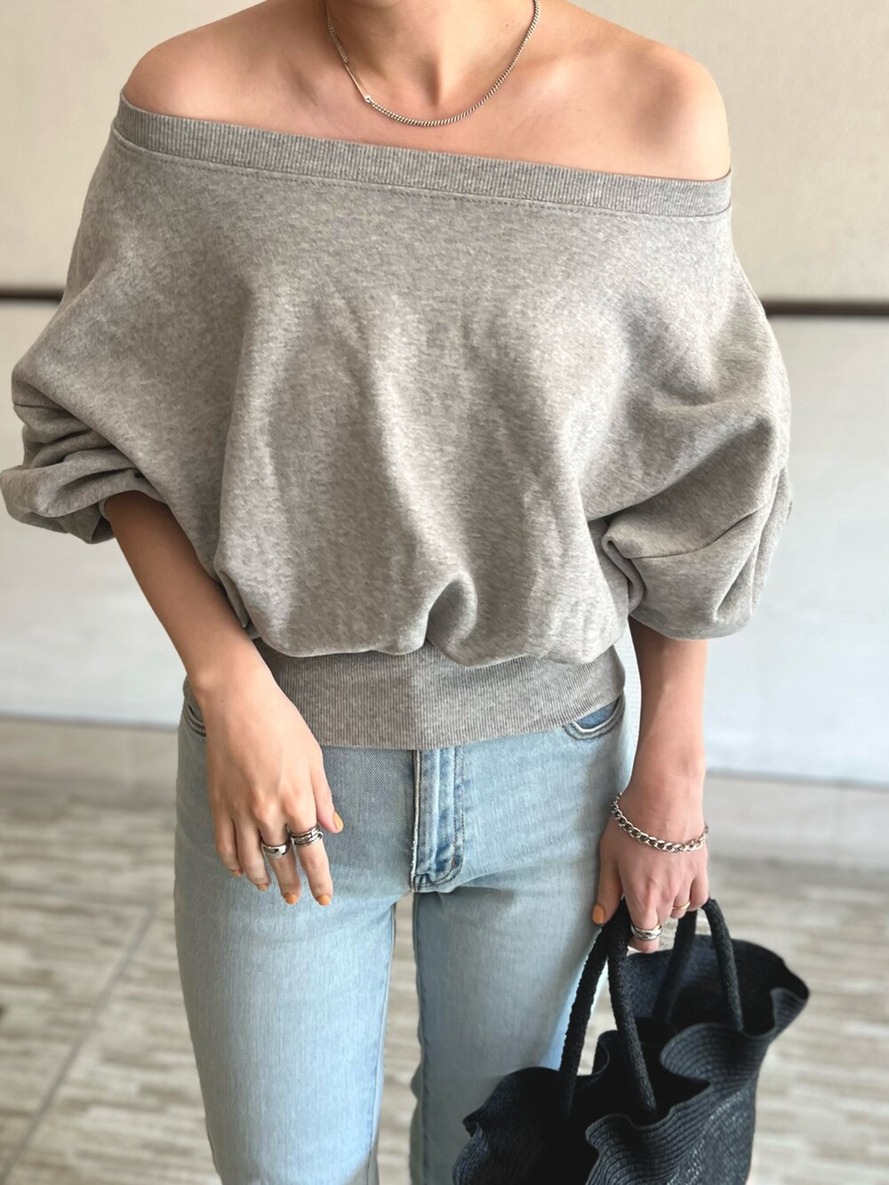 グレー系のスウェット、ブルー系のデニムパンツ、ブラック系のかごバッグを着用したレディースの春コーディネートの3枚目の写真