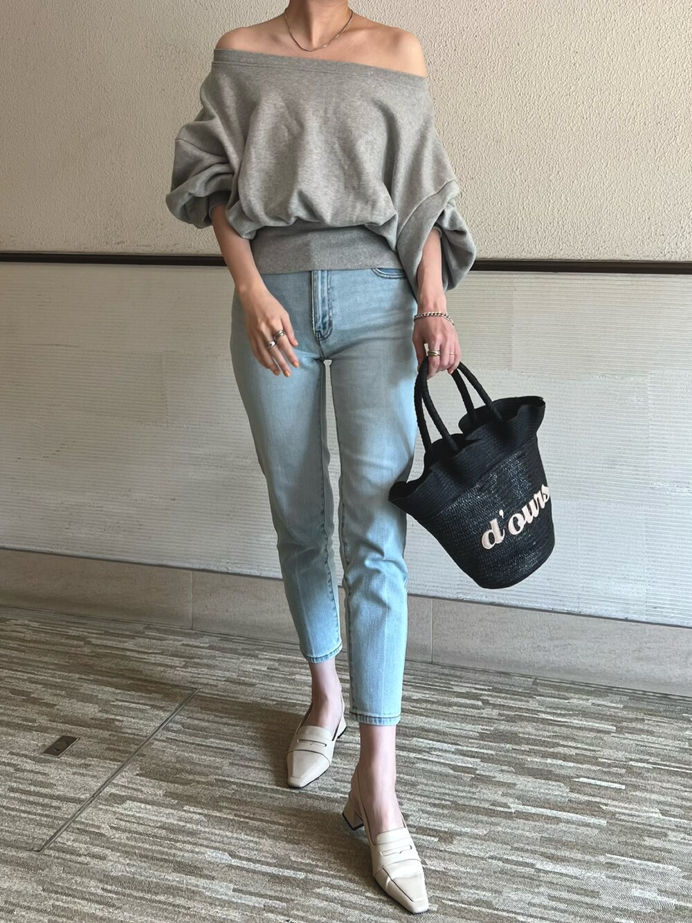 グレー系のスウェット、ブルー系のデニムパンツ、ブラック系のかごバッグを着用したレディースの春コーディネートの5枚目の写真