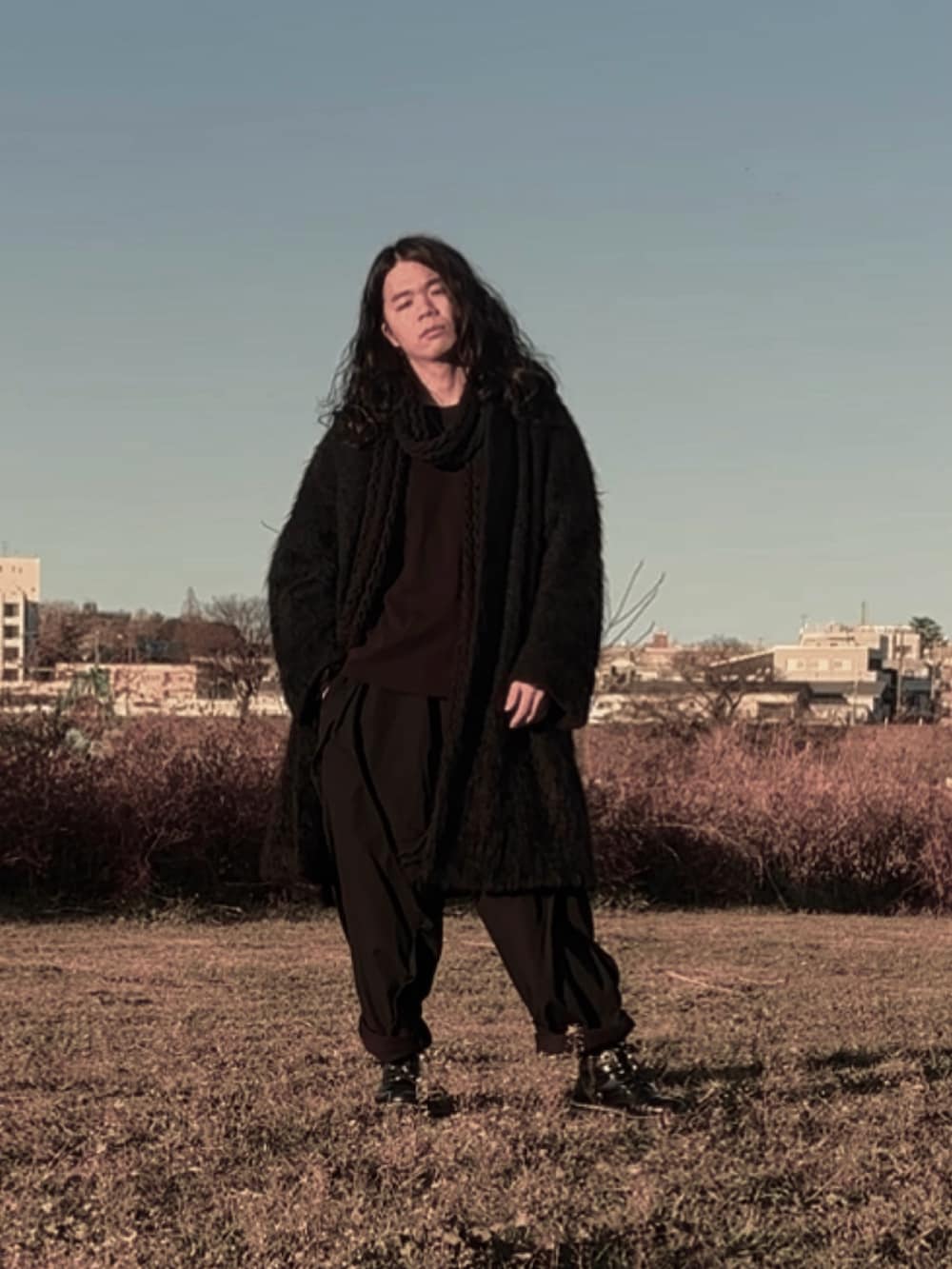 ブラック系のパンツ、ブラック系のチェスターコート、ブラック系のブーツを着用したメンズの冬コーディネートの2枚目の写真