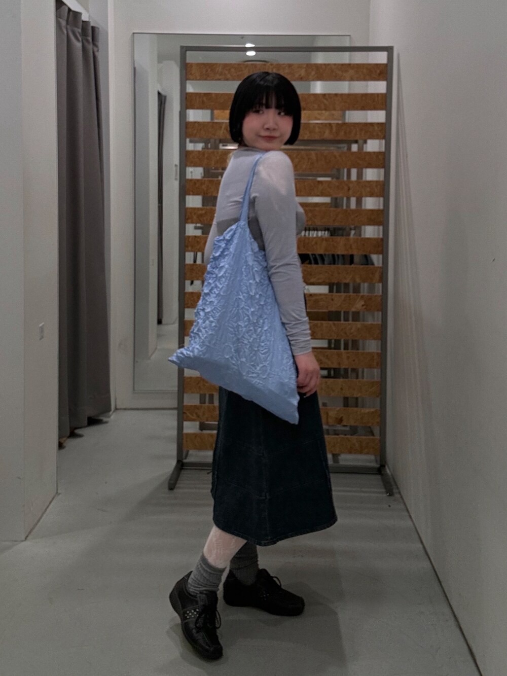 ブルー系のトップス、ブルー系のデニムスカート、ブラック系のスニーカーを着用したレディースの春コーディネートの3枚目の写真