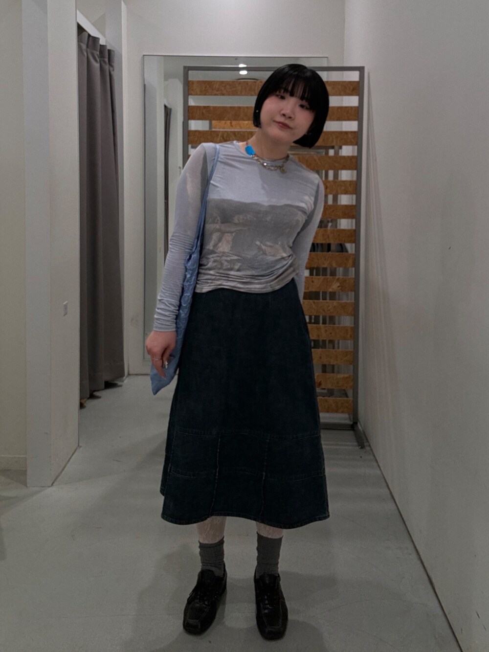 ブルー系のトップス、ブルー系のデニムスカート、ブラック系のスニーカーを着用したレディースの春コーディネートの2枚目の写真