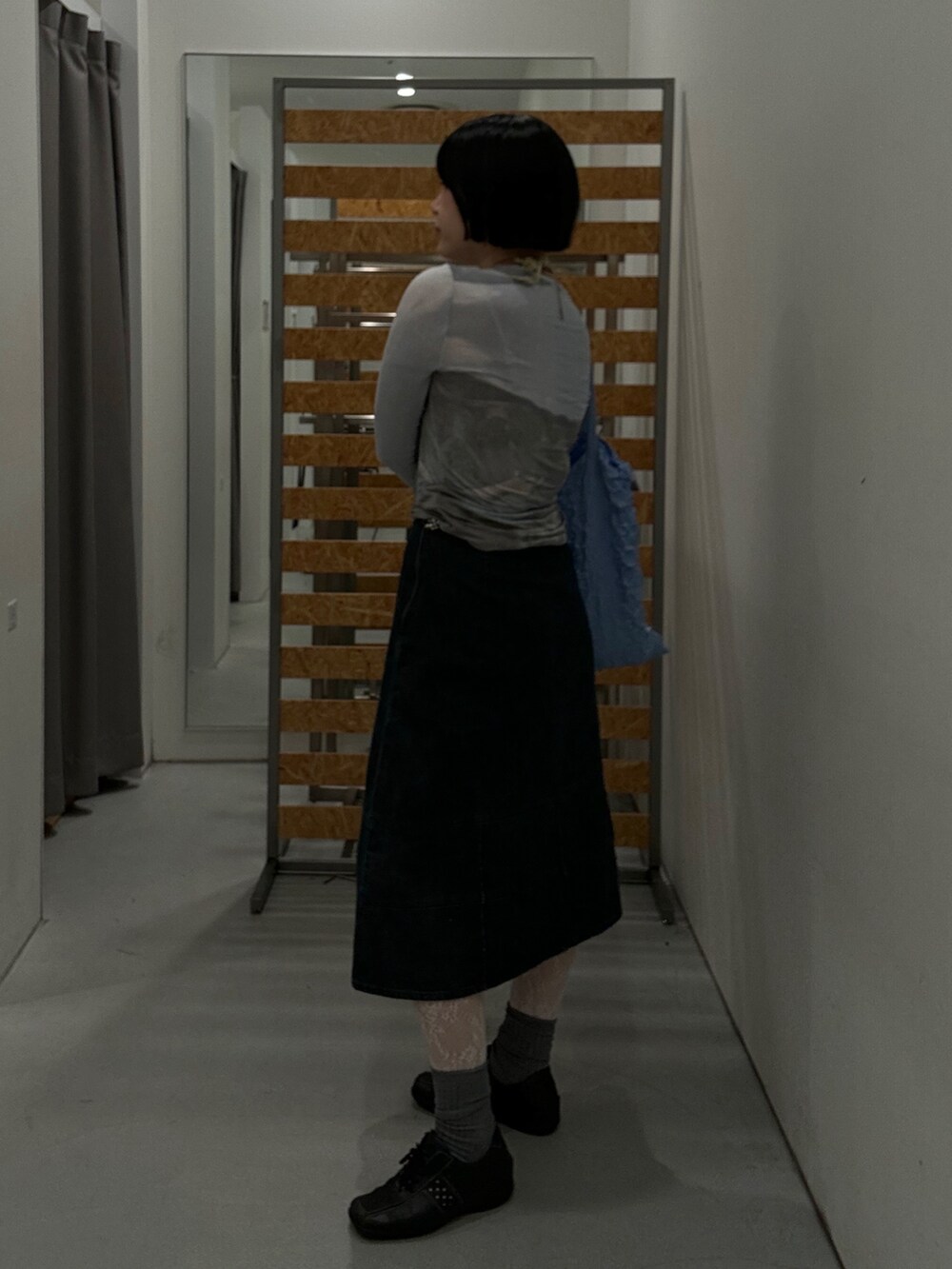 ブルー系のトップス、ブルー系のデニムスカート、ブラック系のスニーカーを着用したレディースの春コーディネートの4枚目の写真