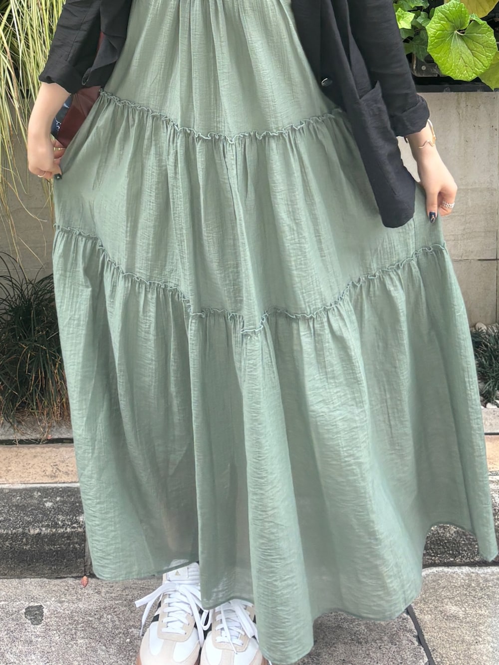 グリーン系のワンピース、ブラック系のテーラードジャケットを着用したレディースの夏コーディネートの5枚目の写真