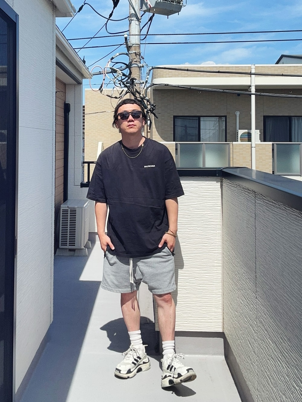 ブラック系のTシャツ/カットソー、グレー系のパンツ、ホワイト系のシューズを着用したメンズの夏コーディネートの2枚目の写真