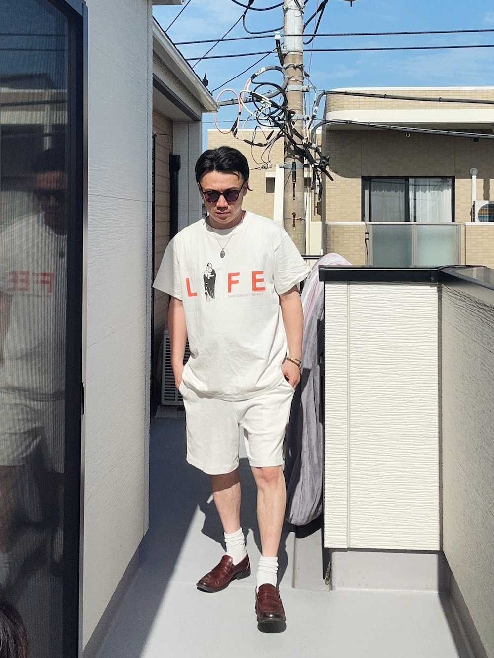 ホワイト系のTシャツ/カットソー、ホワイト系のパンツ、ブラウン系のローファーを着用したメンズの春コーディネートの2枚目の写真