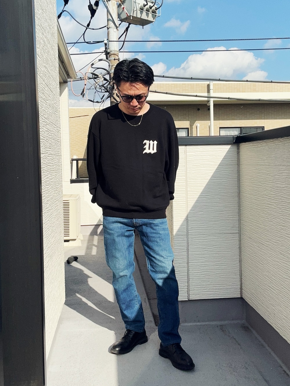 ブルー系のデニムパンツ、ブラック系のスウェット、ブラック系のドレスシューズを着用したメンズの冬コーディネートの2枚目の写真