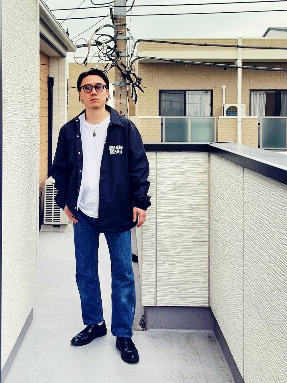 ブルー系のデニムパンツ、ホワイト系のTシャツ/カットソー、ブラック系のジャケット/アウターを着用したメンズの春コーディネートの2枚目の写真