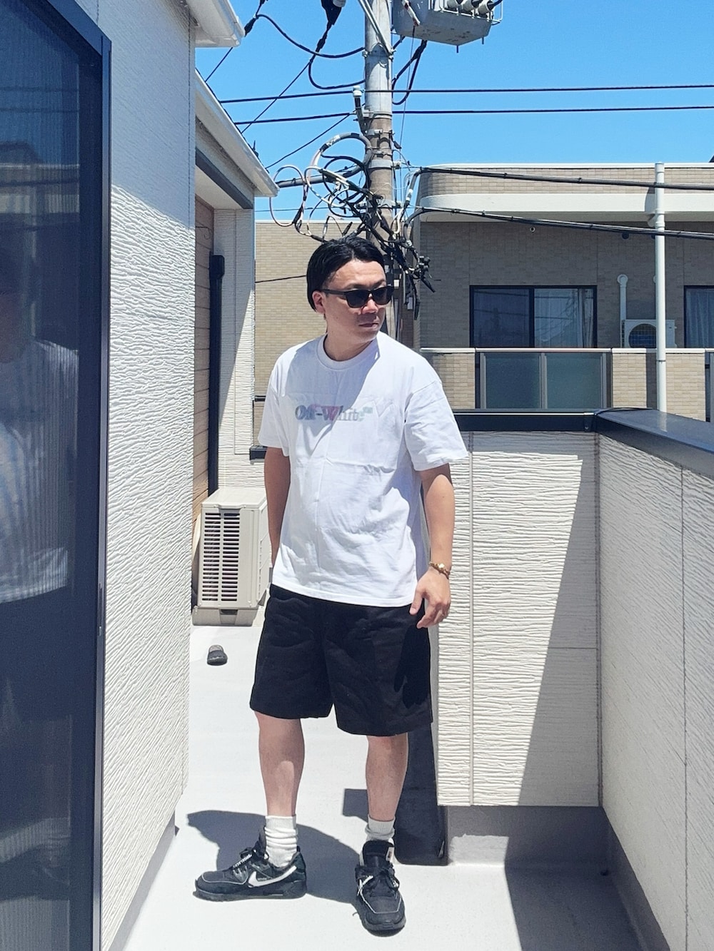 ホワイト系のTシャツ/カットソー、ブラック系のパンツ、ブラック系のスニーカーを着用したメンズの夏コーディネートの3枚目の写真