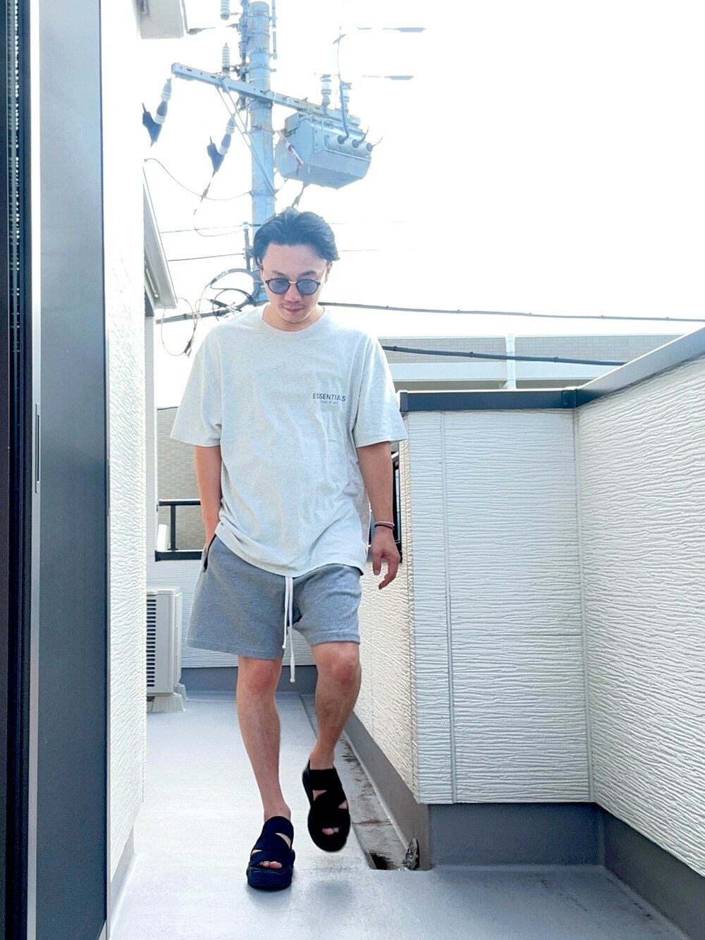グレー系のTシャツ/カットソー、グレー系のパンツ、ブラック系のサンダルを着用したメンズの夏コーディネートの4枚目の写真