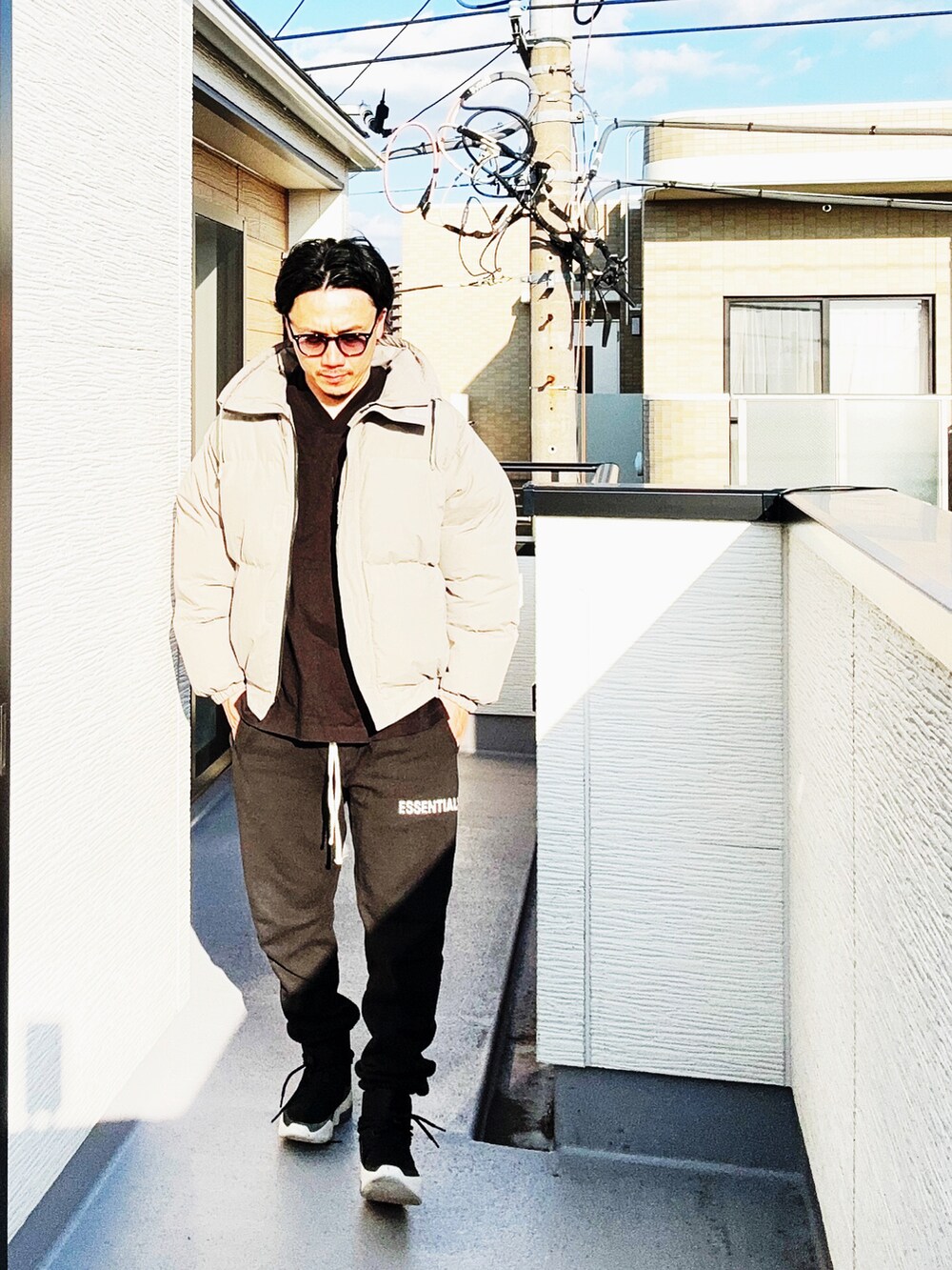 ブラック系のTシャツ/カットソー、グレー系のダウンジャケット/コート、ブラック系のスウェットパンツを着用したメンズの秋コーディネートの2枚目の写真