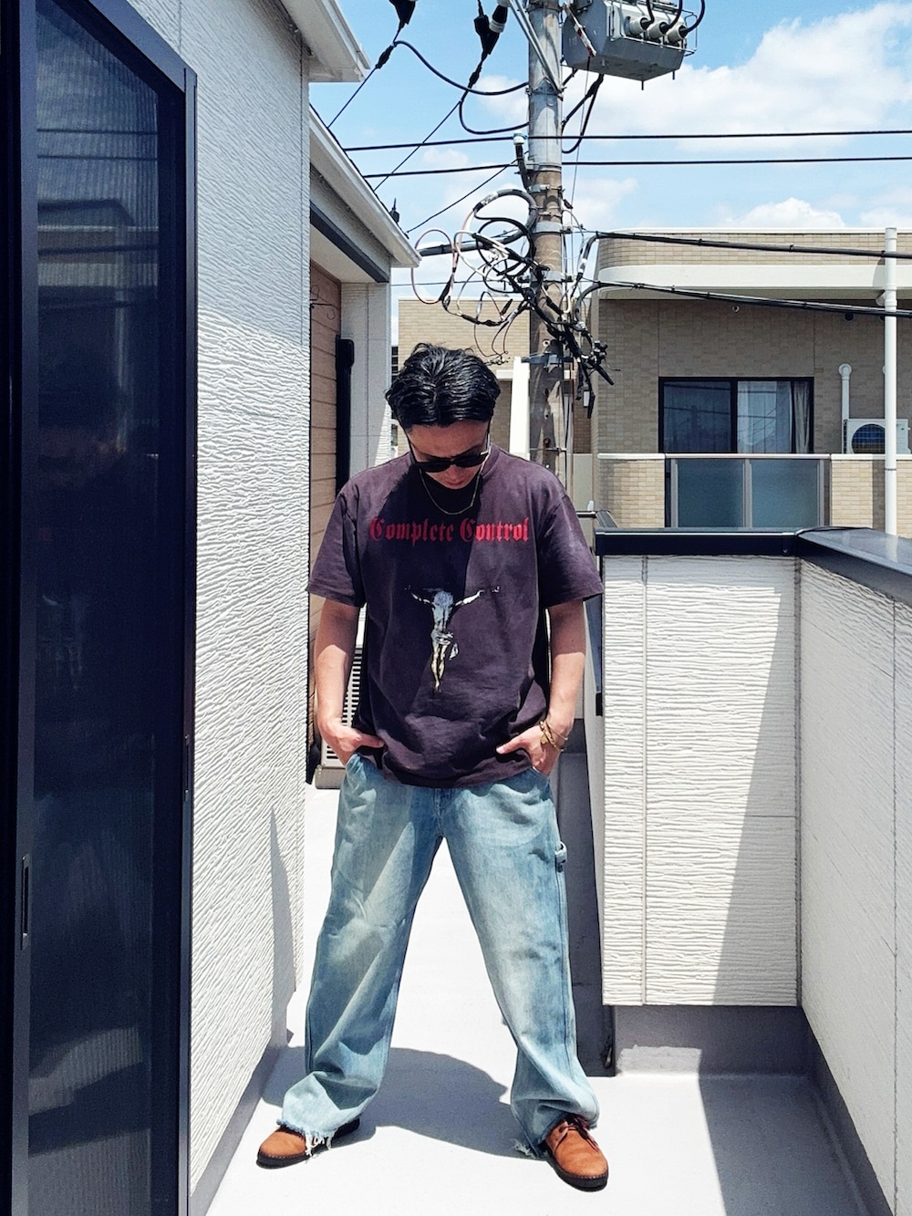 ブルー系のデニムパンツ、ブラック系のTシャツ/カットソー、ブラウン系のドレスシューズを着用したメンズの春コーディネートの3枚目の写真