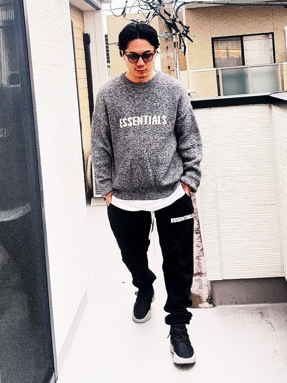 グレー系のニット/セーター、ホワイト系のTシャツ/カットソー、ブラック系のスウェットパンツを着用したメンズの秋コーディネートの3枚目の写真