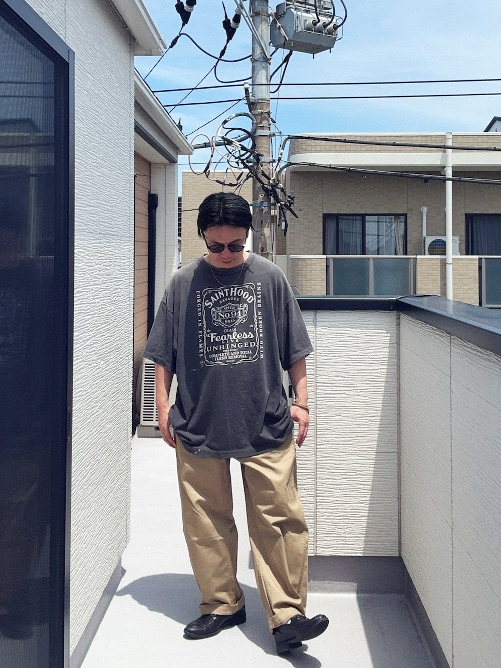 ブラック系のローファー、ブラック系のTシャツ/カットソー、ベージュ系のチノパンツを着用したメンズの夏コーディネートの2枚目の写真
