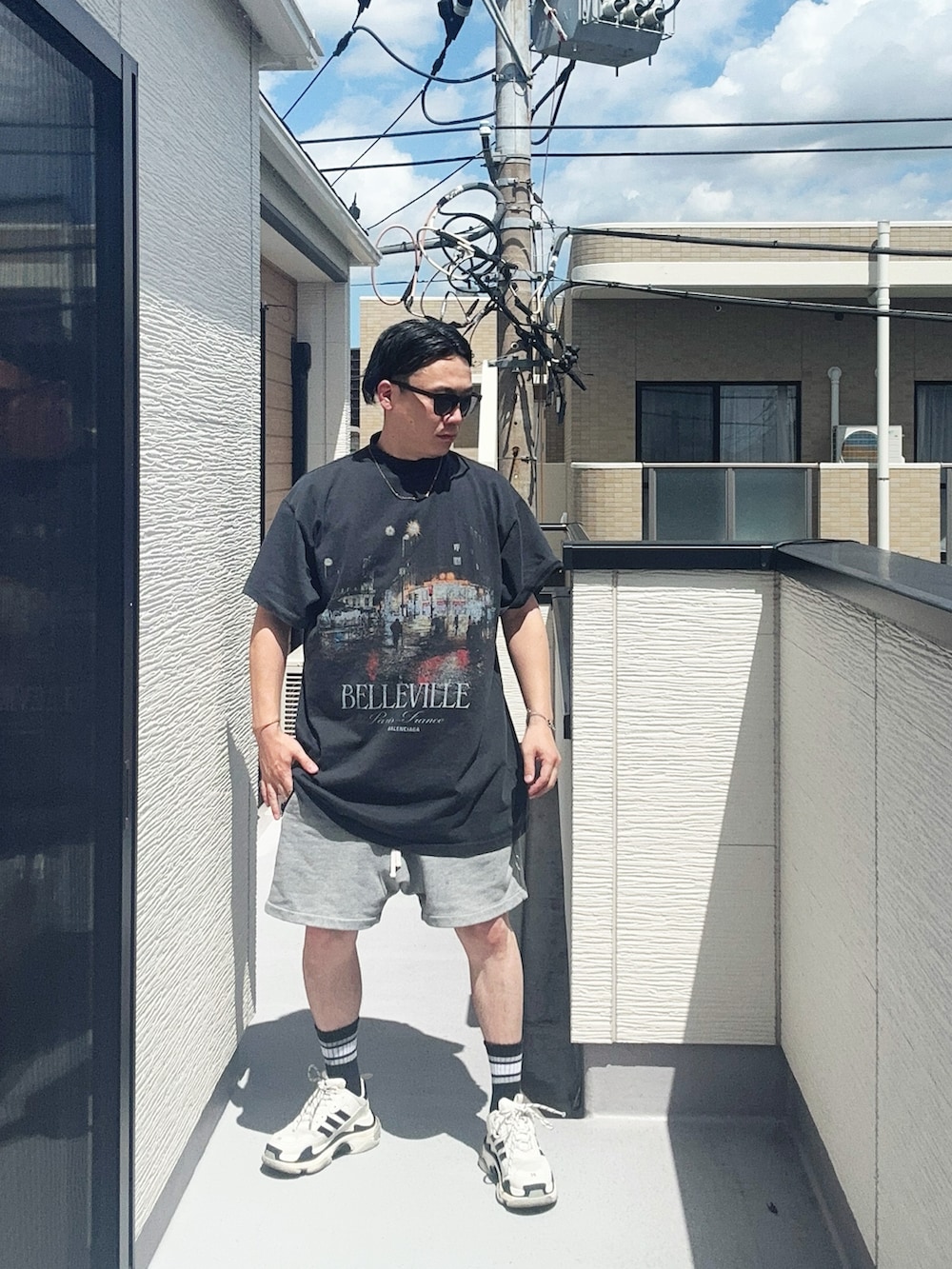 ブラック系のTシャツ/カットソー、グレー系のパンツ、ホワイト系のシューズを着用したメンズの夏コーディネートの2枚目の写真
