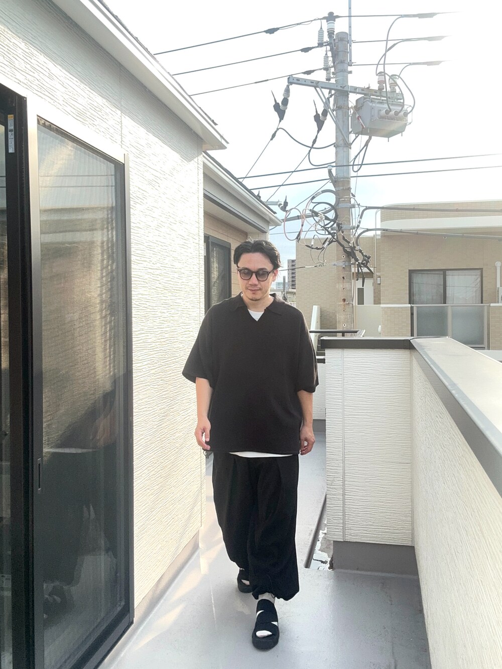 ブラック系のポロシャツ、ブラック系のスウェットパンツ、ブラック系のサンダルを着用したメンズの夏コーディネートの3枚目の写真