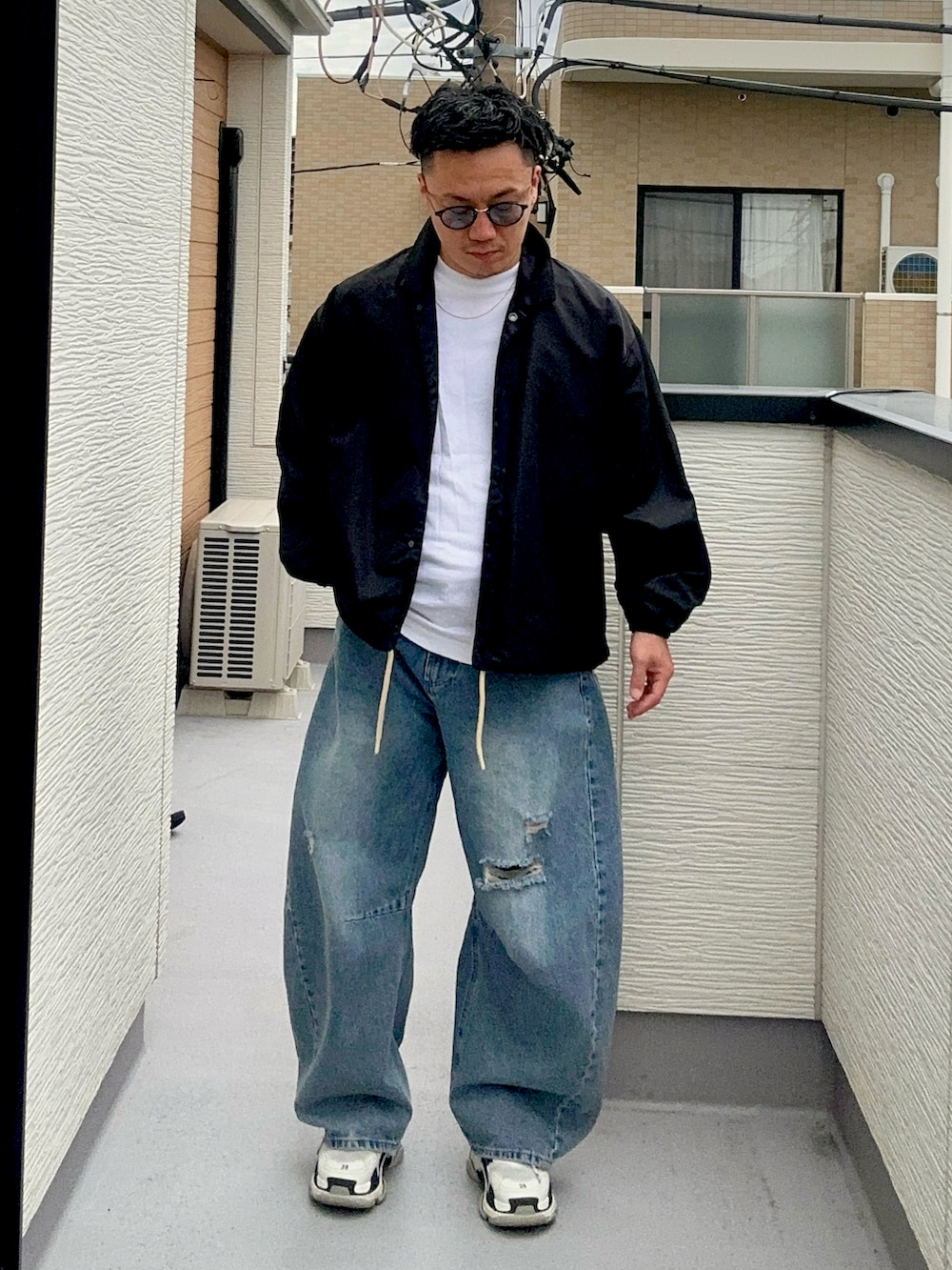 ブルー系のデニムパンツ、ブラック系のナイロンジャケット、ホワイト系のTシャツ/カットソーを着用したメンズの秋コーディネートの2枚目の写真