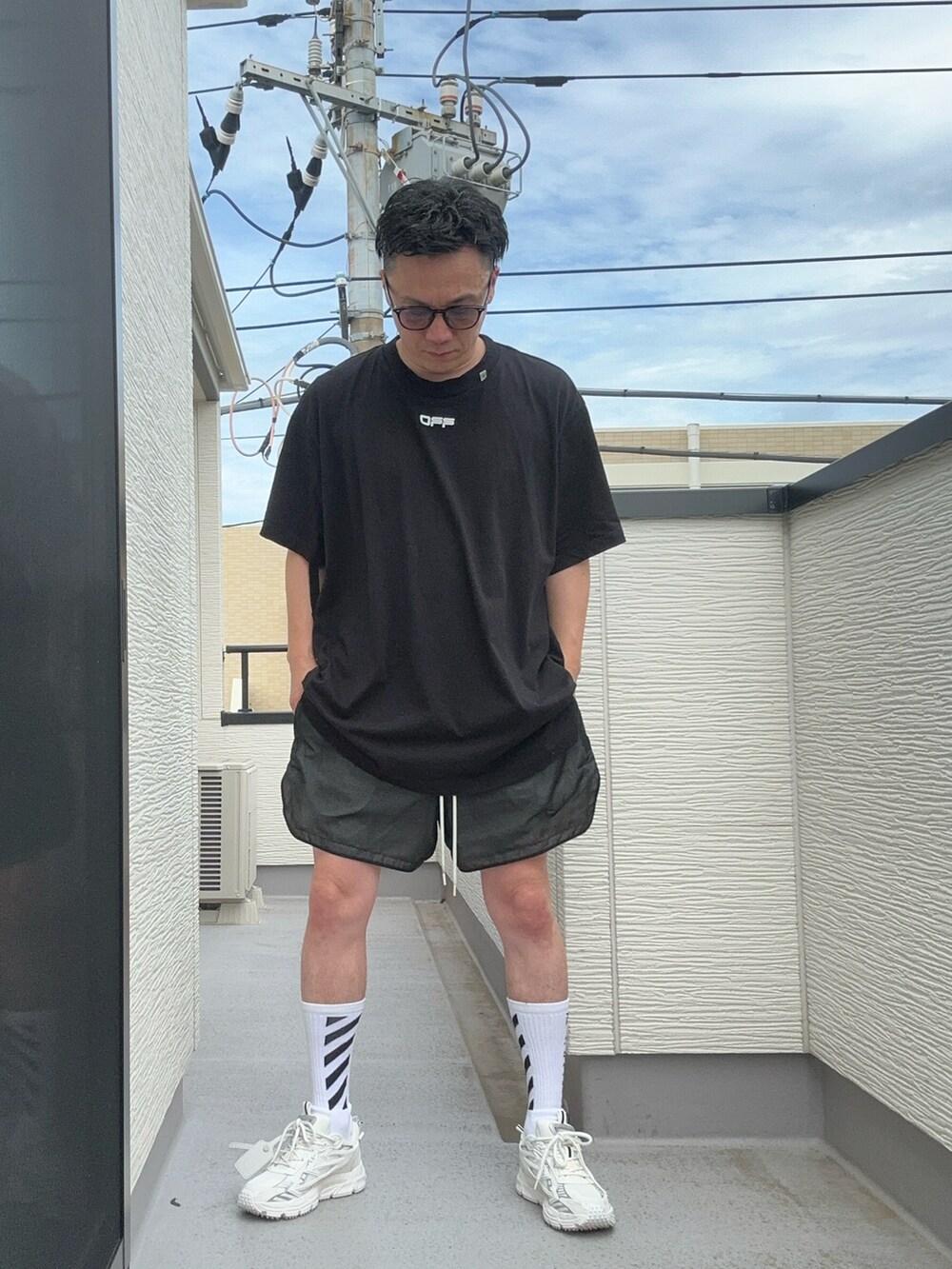 ブラック系のTシャツ/カットソー、ホワイト系のスニーカー、ブラック系のパンツを着用したメンズの夏コーディネートの4枚目の写真