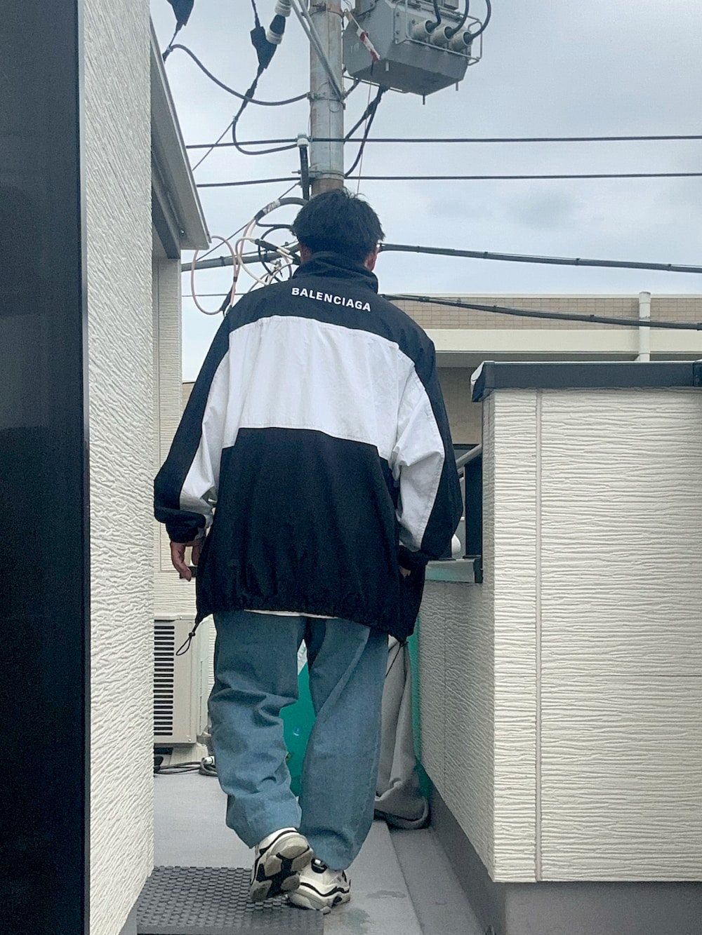 ホワイト系のTシャツ/カットソー、ブラック系のナイロンジャケット、ブルー系のデニムパンツを着用したメンズの秋コーディネートの2枚目の写真