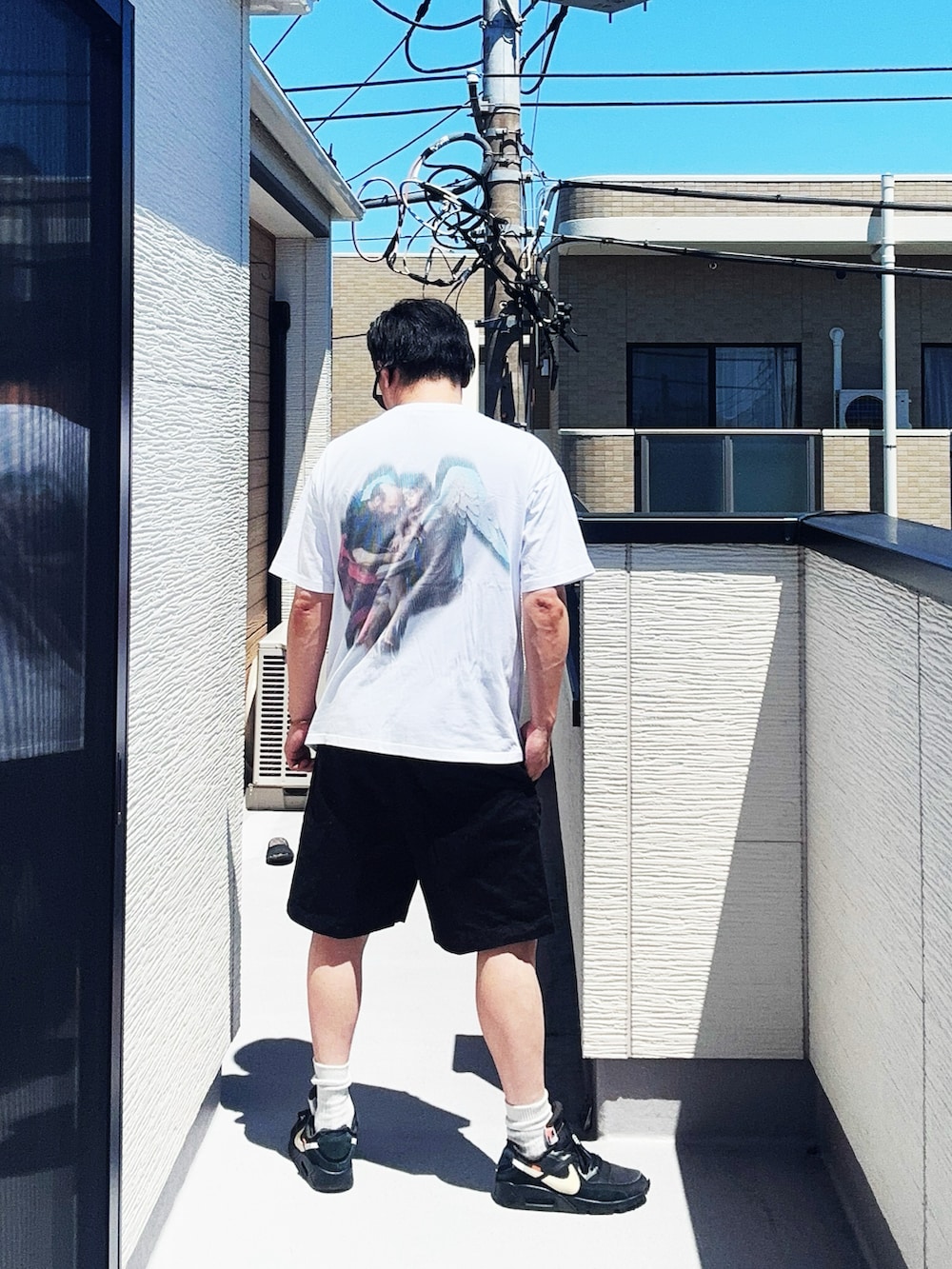 ホワイト系のTシャツ/カットソー、ブラック系のパンツ、ブラック系のスニーカーを着用したメンズの夏コーディネートの4枚目の写真
