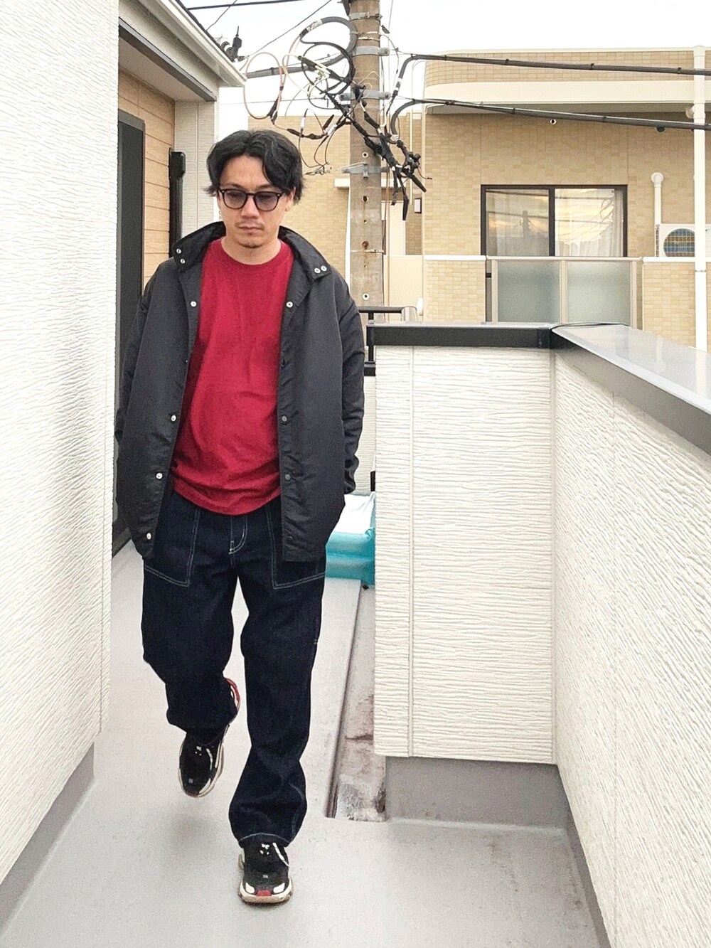 レッド系のTシャツ/カットソー、ブルー系のデニムパンツ、ブラック系のシューズを着用したメンズの秋コーディネートの2枚目の写真