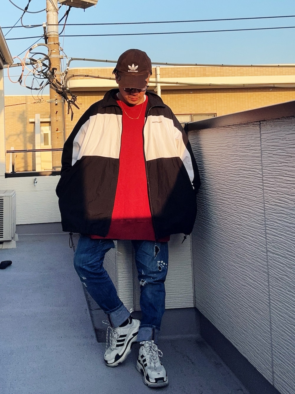 レッド系のスウェット、ブルー系のデニムパンツ、ブラック系のナイロンジャケットを着用したメンズの冬コーディネートの2枚目の写真