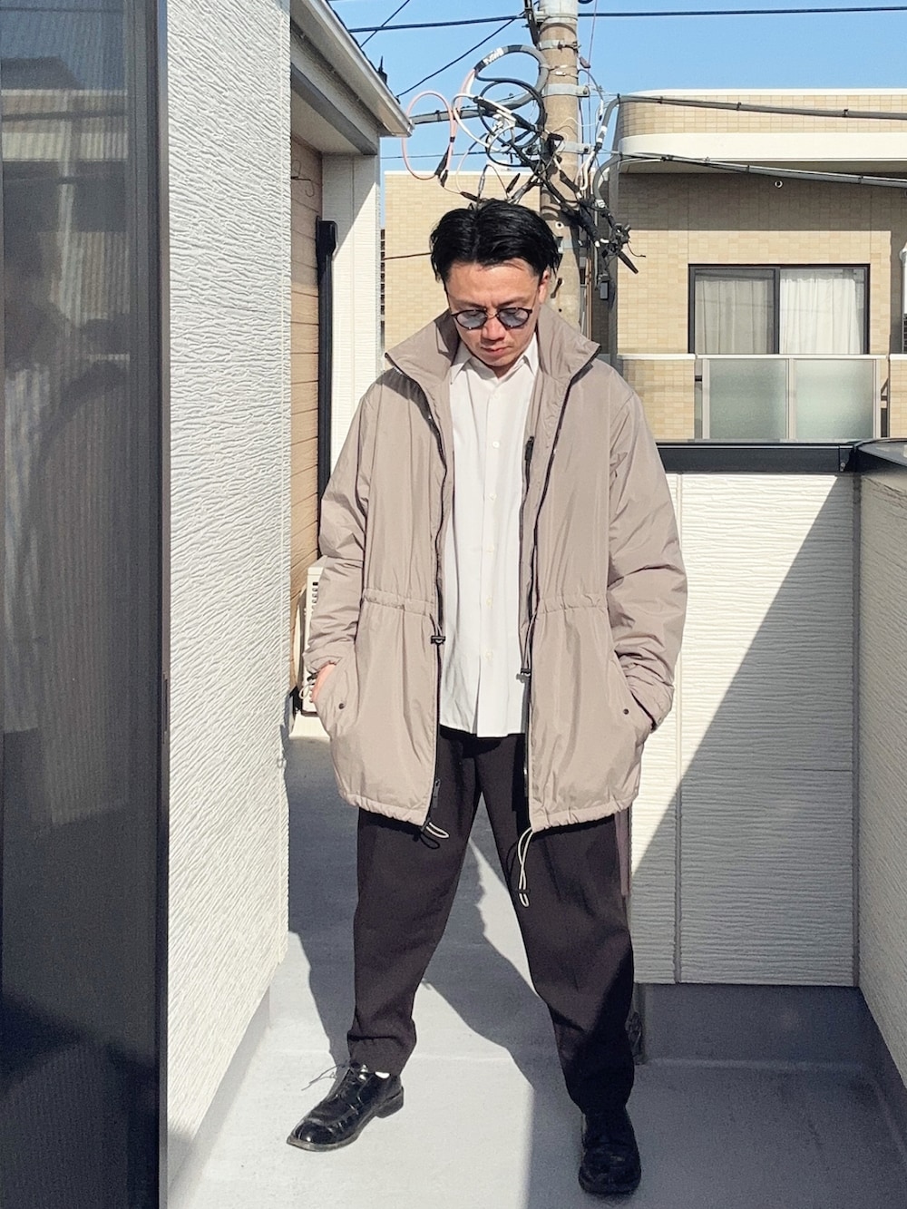 ベージュ系のその他アウター、ブラック系のスラックス、ホワイト系のシャツ/ブラウスを着用したメンズの春コーディネートの2枚目の写真