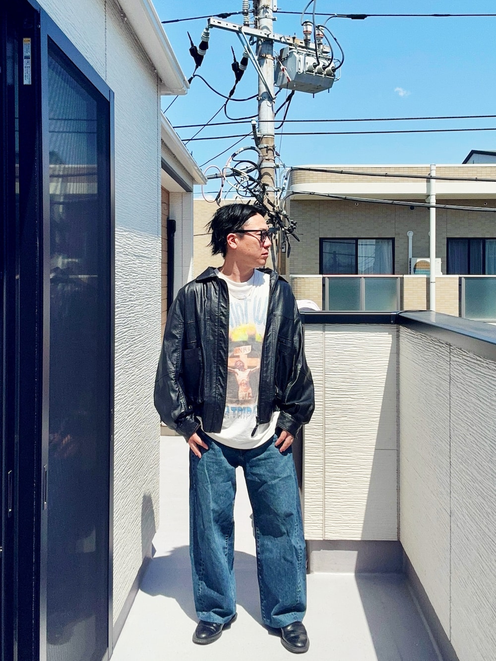 ブラック系のブルゾン、ホワイト系のTシャツ/カットソー、ブルー系のデニムパンツを着用したメンズの春コーディネートの2枚目の写真