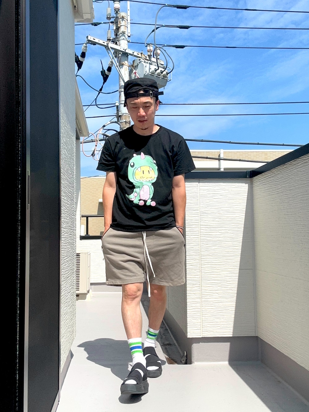 ブラック系のTシャツ/カットソー、グレー系のスウェットパンツ、ブラック系のサンダルを着用したメンズの夏コーディネートの2枚目の写真