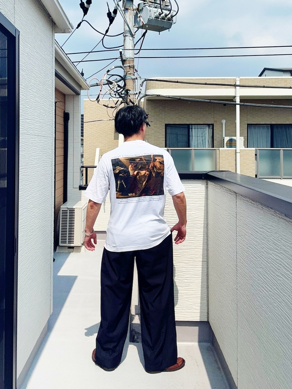 ブラック系のスラックス、ホワイト系のTシャツ/カットソー、ブラウン系のローファーを着用したメンズの夏コーディネートの3枚目の写真