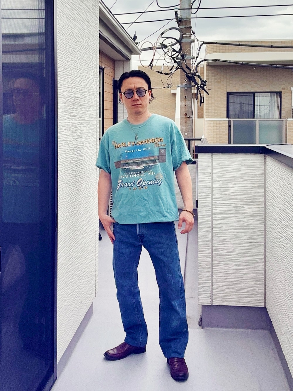 ブルー系のデニムパンツ、ブルー系のTシャツ/カットソー、ブラウン系のローファーを着用したメンズの春コーディネートの2枚目の写真