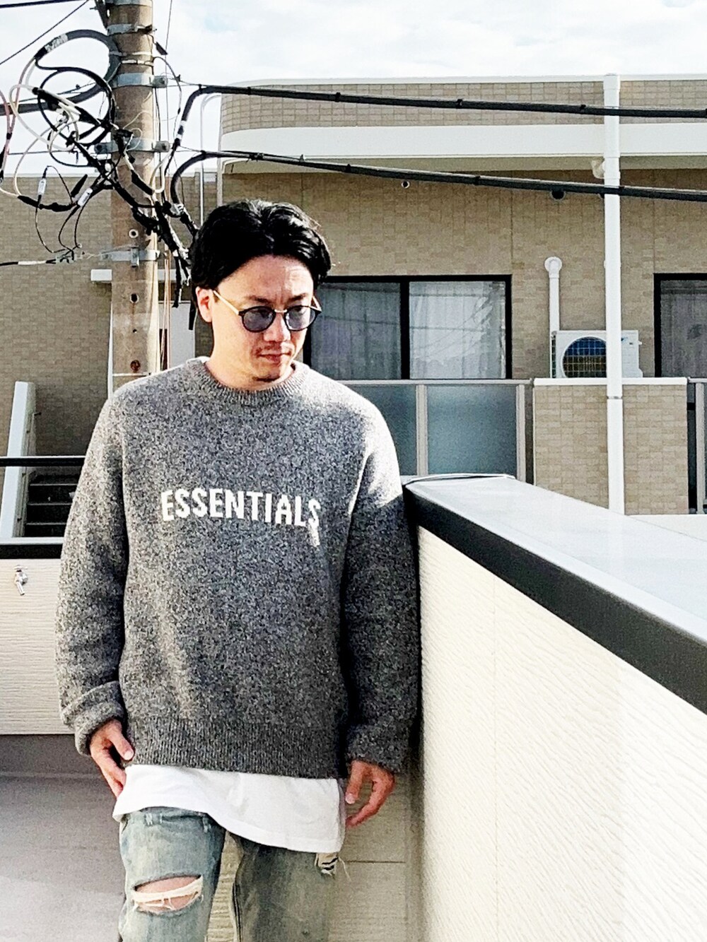 グレー系のニット/セーター、ホワイト系のTシャツ/カットソー、ブルー系のデニムパンツを着用したメンズの秋コーディネートの2枚目の写真