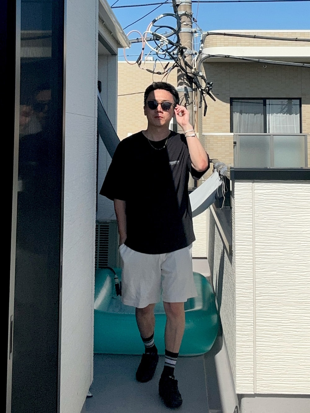 ブラック系のTシャツ/カットソー、ホワイト系のパンツ、ブラック系のシューズを着用したメンズの夏コーディネートの2枚目の写真