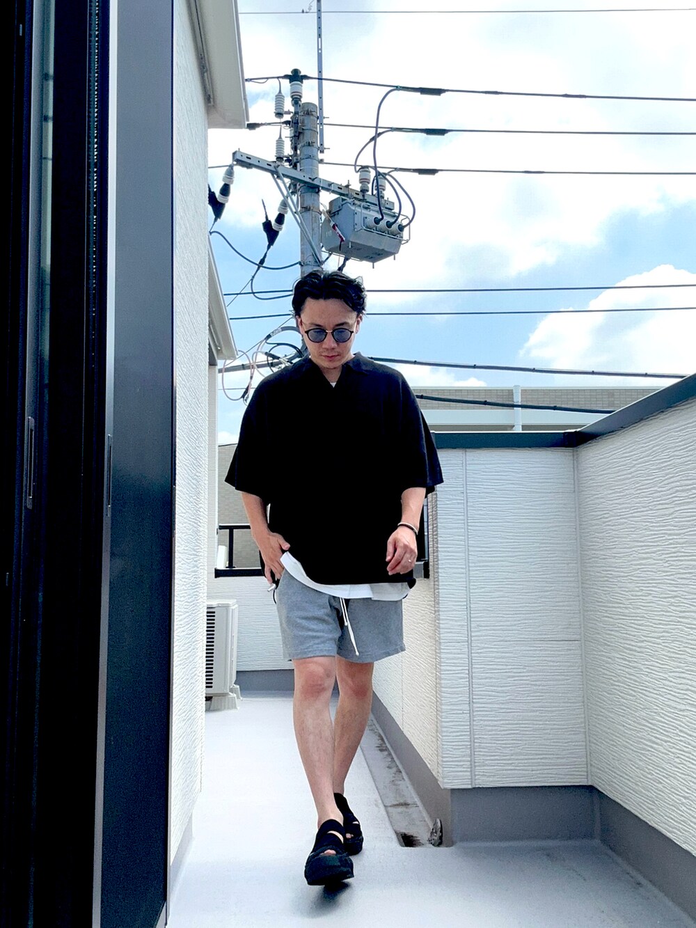 ブラック系のポロシャツ、グレー系のパンツ、ホワイト系のTシャツ/カットソーを着用したメンズの夏コーディネートの4枚目の写真