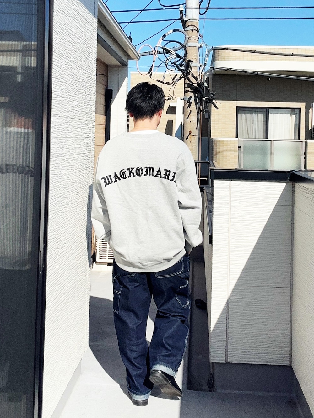 ブルー系のデニムパンツ、グレー系のスウェット、ブラック系のドレスシューズを着用したメンズの春コーディネートの3枚目の写真