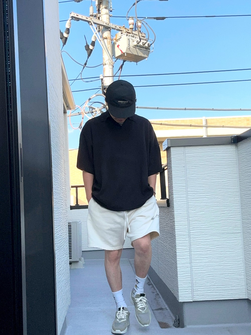 ホワイト系のスウェットパンツ、ブラック系のポロシャツ、グレー系のスニーカーを着用したメンズの夏コーディネートの3枚目の写真