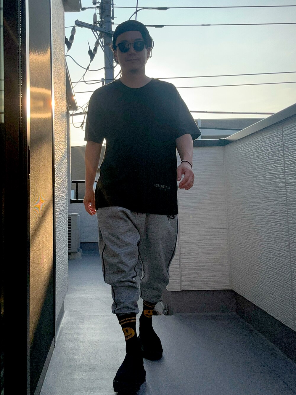 ブラック系のTシャツ/カットソー、グレー系のパンツ、ブラック系のサンダルを着用したメンズの夏コーディネートの5枚目の写真