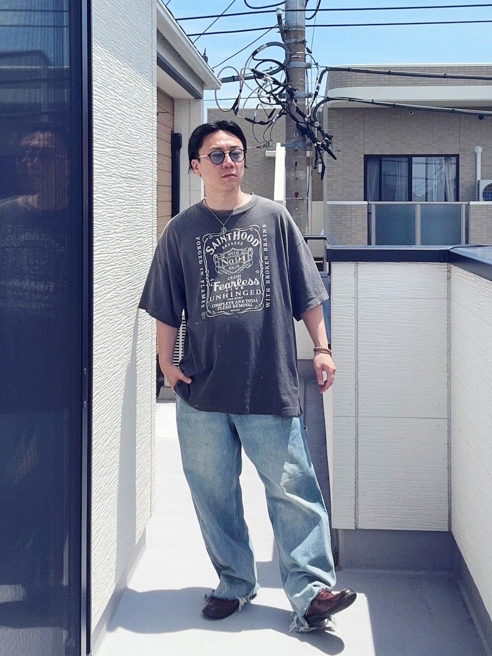 ブルー系のデニムパンツ、ブラック系のTシャツ/カットソー、ブラウン系のローファーを着用したメンズの夏コーディネートの2枚目の写真