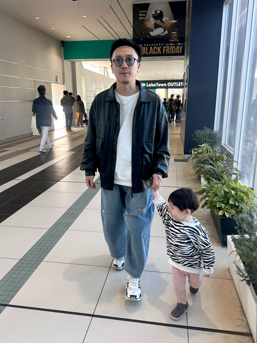 ブラック系のブルゾン、ブルー系のデニムパンツ、ホワイト系のスウェットを着用したメンズの秋コーディネートの4枚目の写真