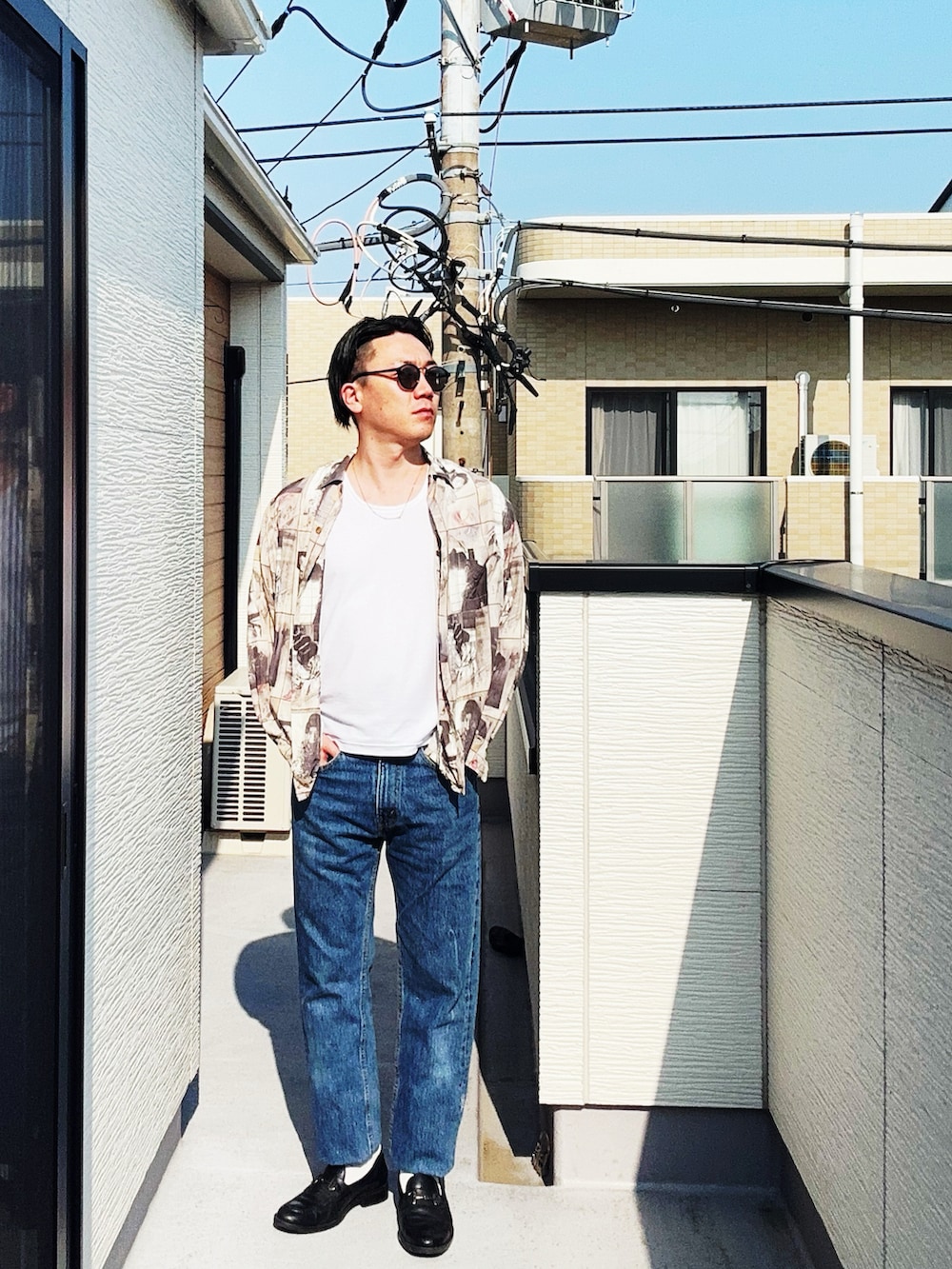 ブルー系のデニムパンツ、ブラック系のローファー、ホワイト系のタンクトップを着用したメンズの春コーディネートの2枚目の写真