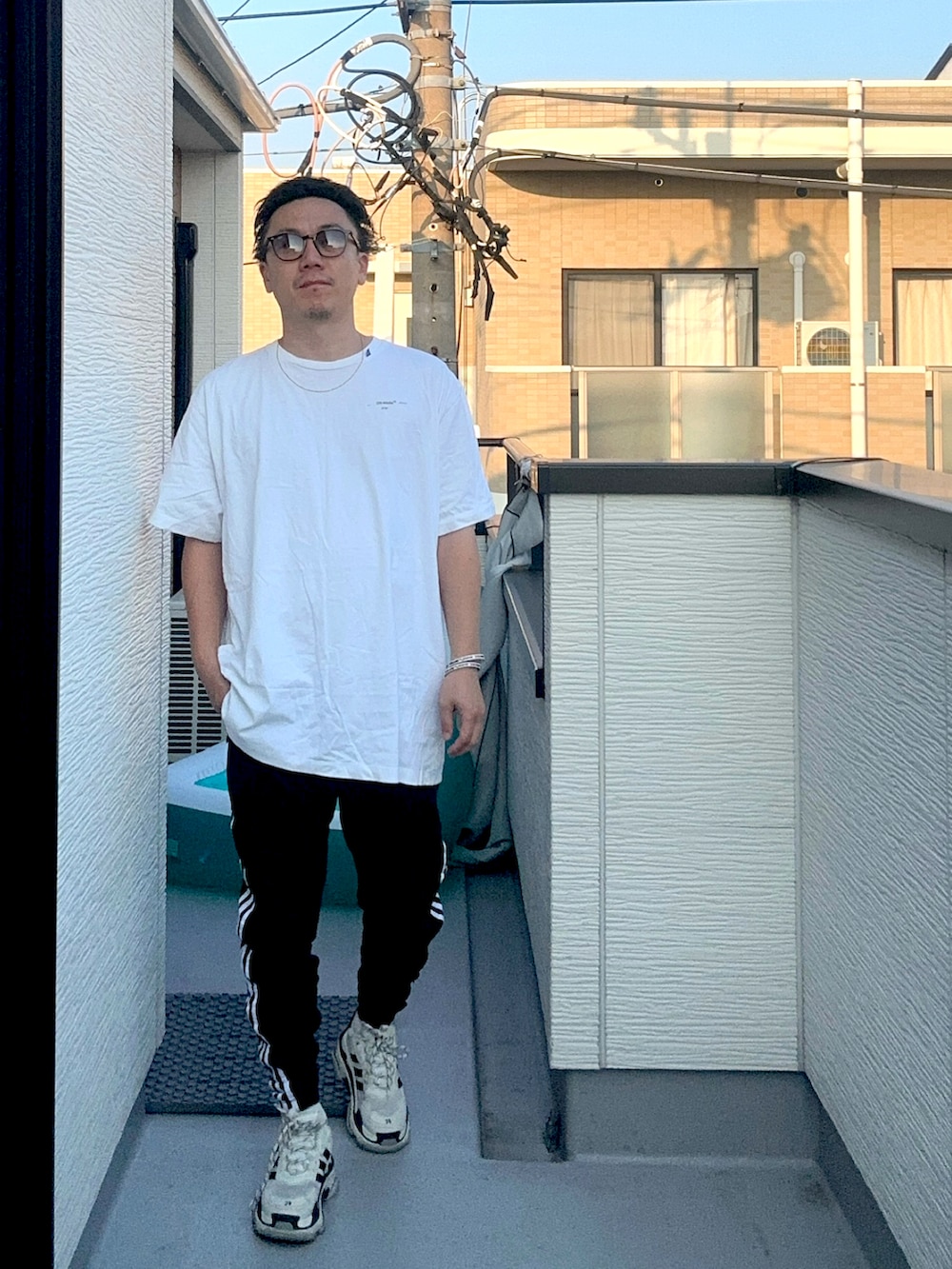 ブラック系のスウェットパンツ、ホワイト系のトップス、ホワイト系のシューズを着用したメンズの秋コーディネートの2枚目の写真