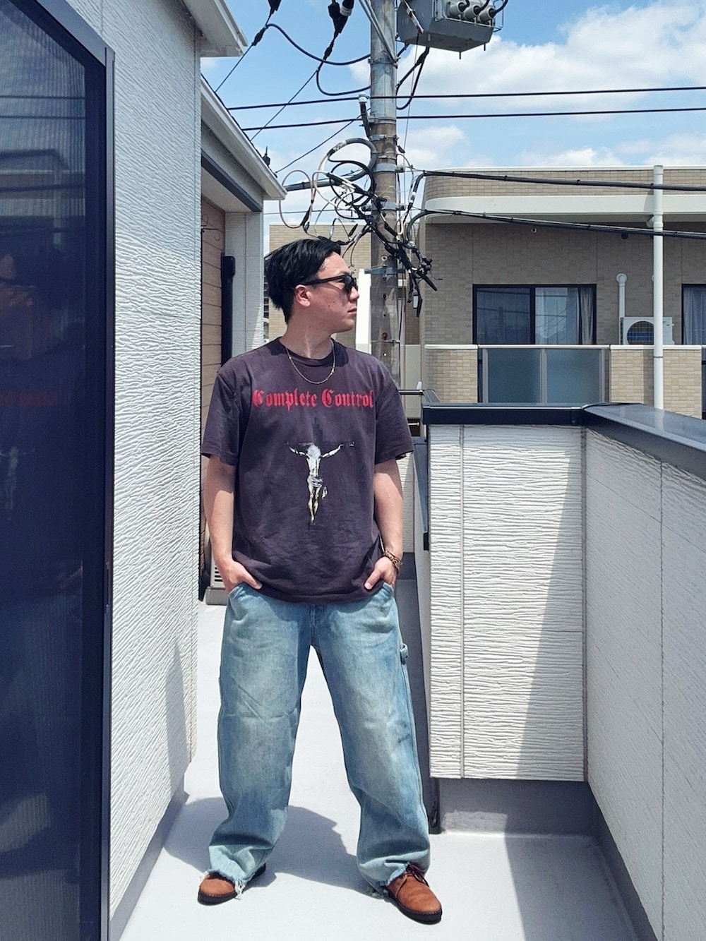 ブルー系のデニムパンツ、ブラック系のTシャツ/カットソー、ブラウン系のドレスシューズを着用したメンズの春コーディネートの2枚目の写真