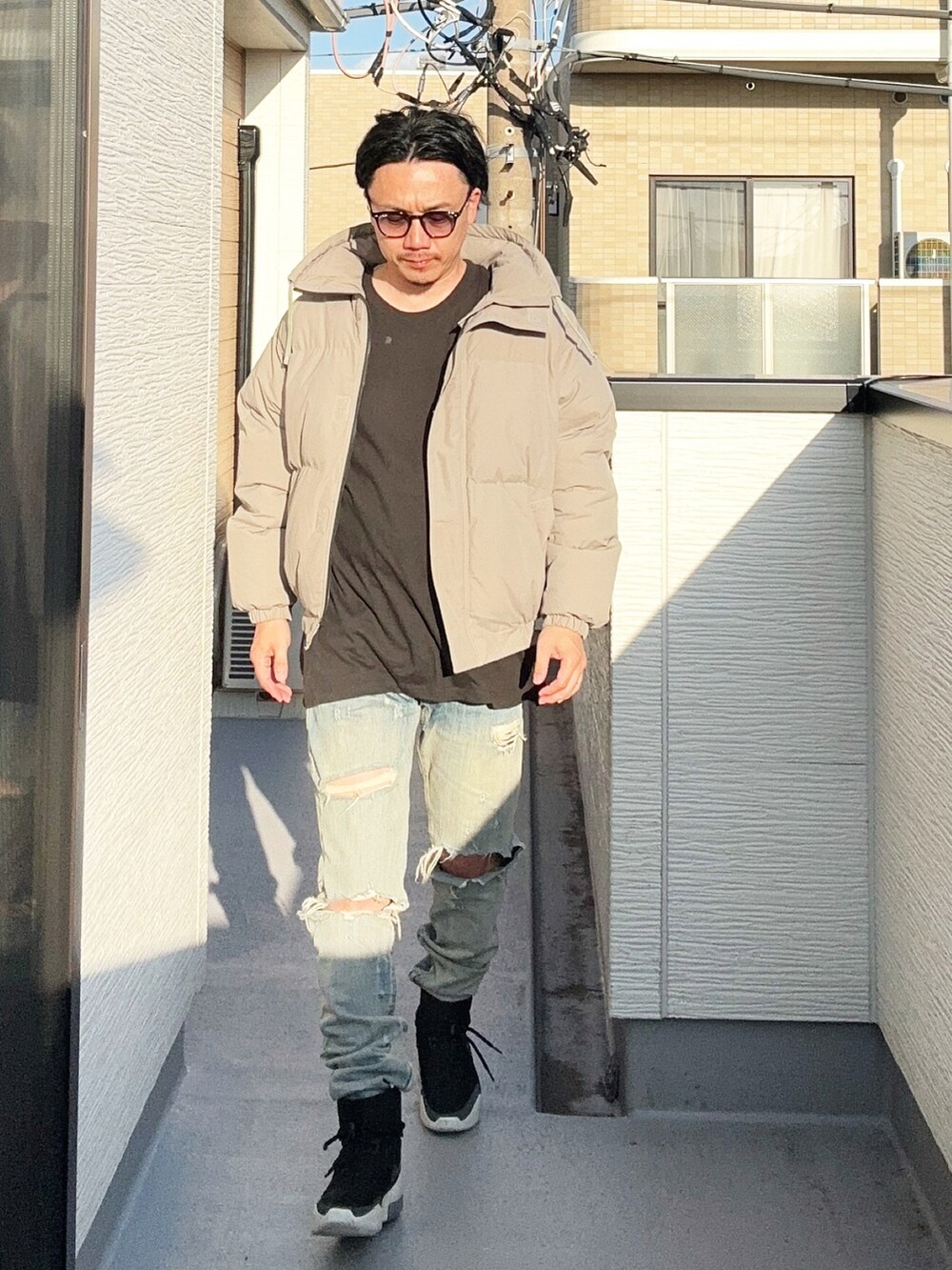 グレー系のダウンジャケット/コート、ブラック系のTシャツ/カットソー、ブルー系のデニムパンツを着用したメンズの秋コーディネートの2枚目の写真