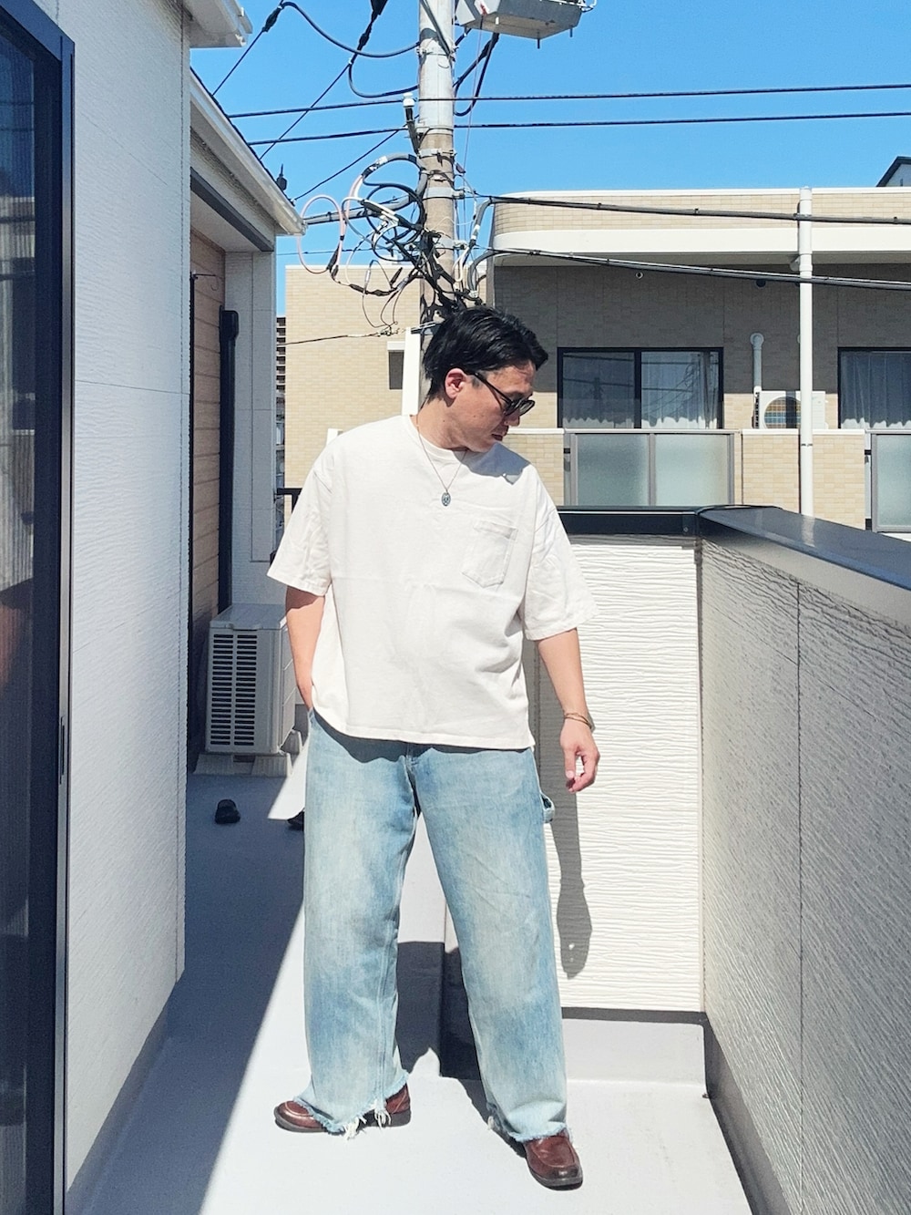 ブルー系のデニムパンツ、ホワイト系のTシャツ/カットソー、ブラウン系のローファーを着用したメンズの夏コーディネートの3枚目の写真
