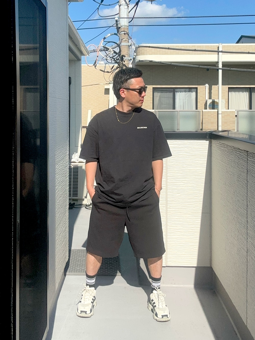 ブラック系のTシャツ/カットソー、ブラック系のスウェットパンツ、ホワイト系のシューズを着用したメンズの秋コーディネートの2枚目の写真