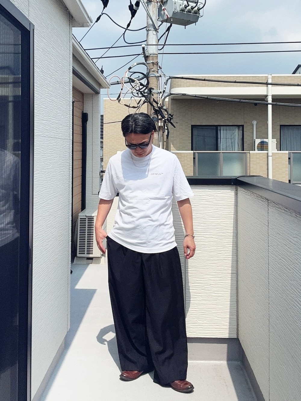 ブラック系のスラックス、ホワイト系のTシャツ/カットソー、ブラウン系のローファーを着用したメンズの夏コーディネートの2枚目の写真